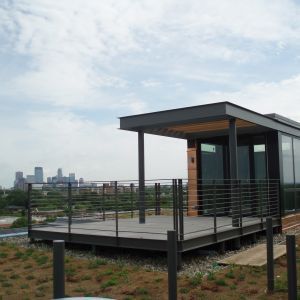 Modern rooftop deck with a city skyline in the background; gray deck with metal railing and supports.