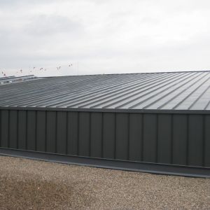 Gray corrugated metal roof on a building, under a cloudy sky.