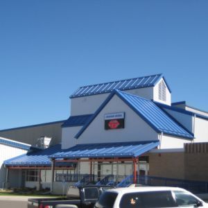 Building with blue roof and trim, red sign, and white exterior under a blue sky.
