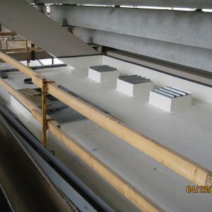 White rooftop with three ventilation units, wood scaffolding, and metal beams.