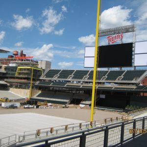 Baseball stadium under a blue sky, with empty seats and a scoreboard.