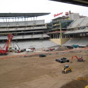 Construction site at a stadium. Heavy machinery on a dirt field with the stadium stands being rebuilt.