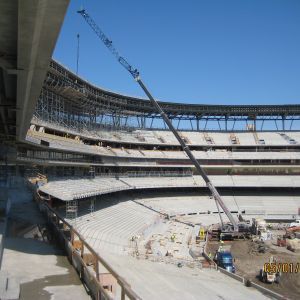 Construction of a stadium with a tall crane lifting materials.