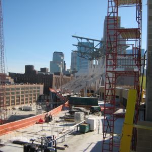 Construction site with city skyline backdrop, featuring scaffolding, building materials, and partially built structure.