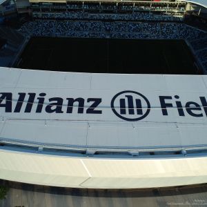 Allianz Field stadium from above, white roof with logo and black text, green field below filled with people.