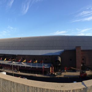 Large brick building with a curved metal roof, various flags, and a blue sky.