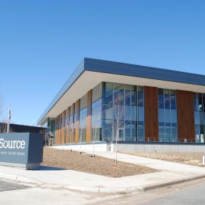 Modern building with large windows and brown paneling; sign reads