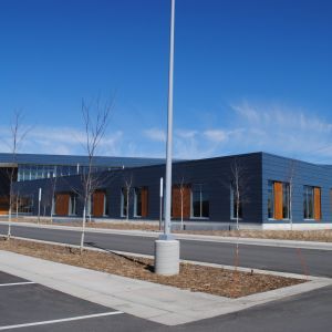 Blue building with rectangular windows and a tall, silver pole on a sunny day.