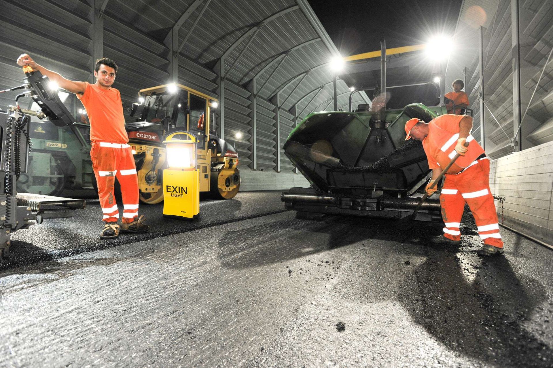 A group of construction workers are working on a road at night.