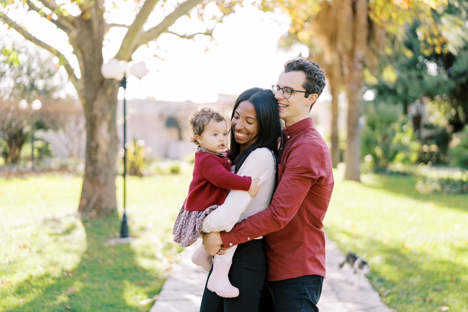 A man and woman are holding a baby in a park.
