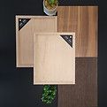 Planches à découper en bois de différentes couleurs, avec un fond végétal et sombre.