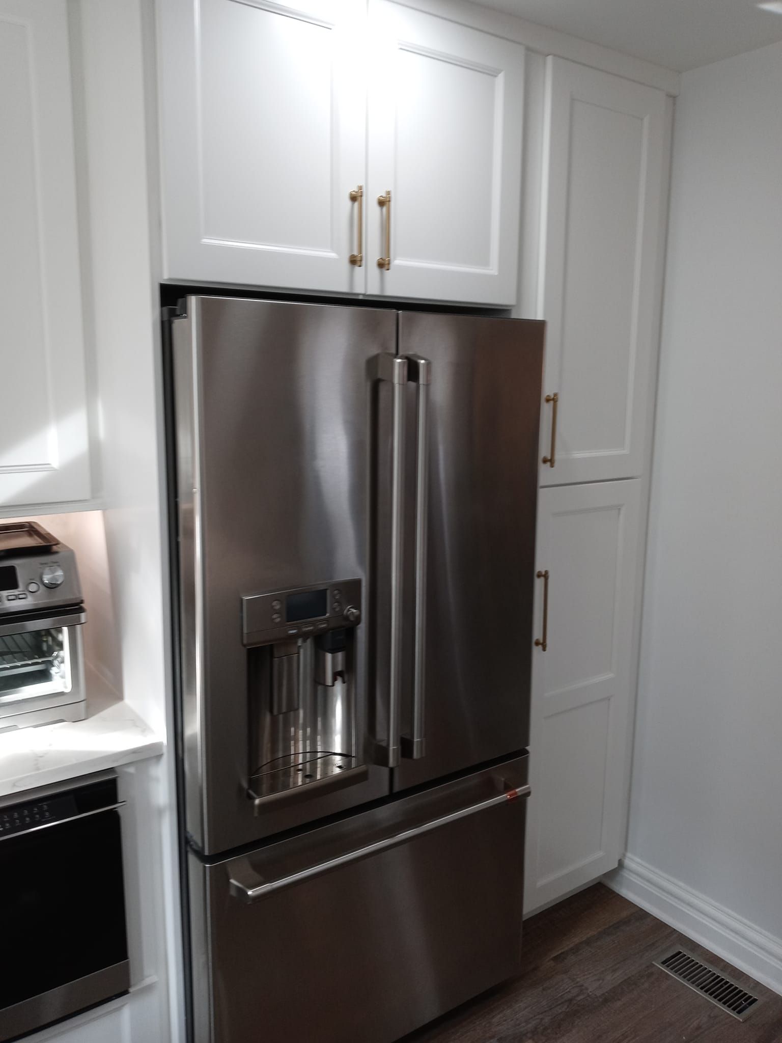 Stainless steel refrigerator in white kitchen cabinetry.