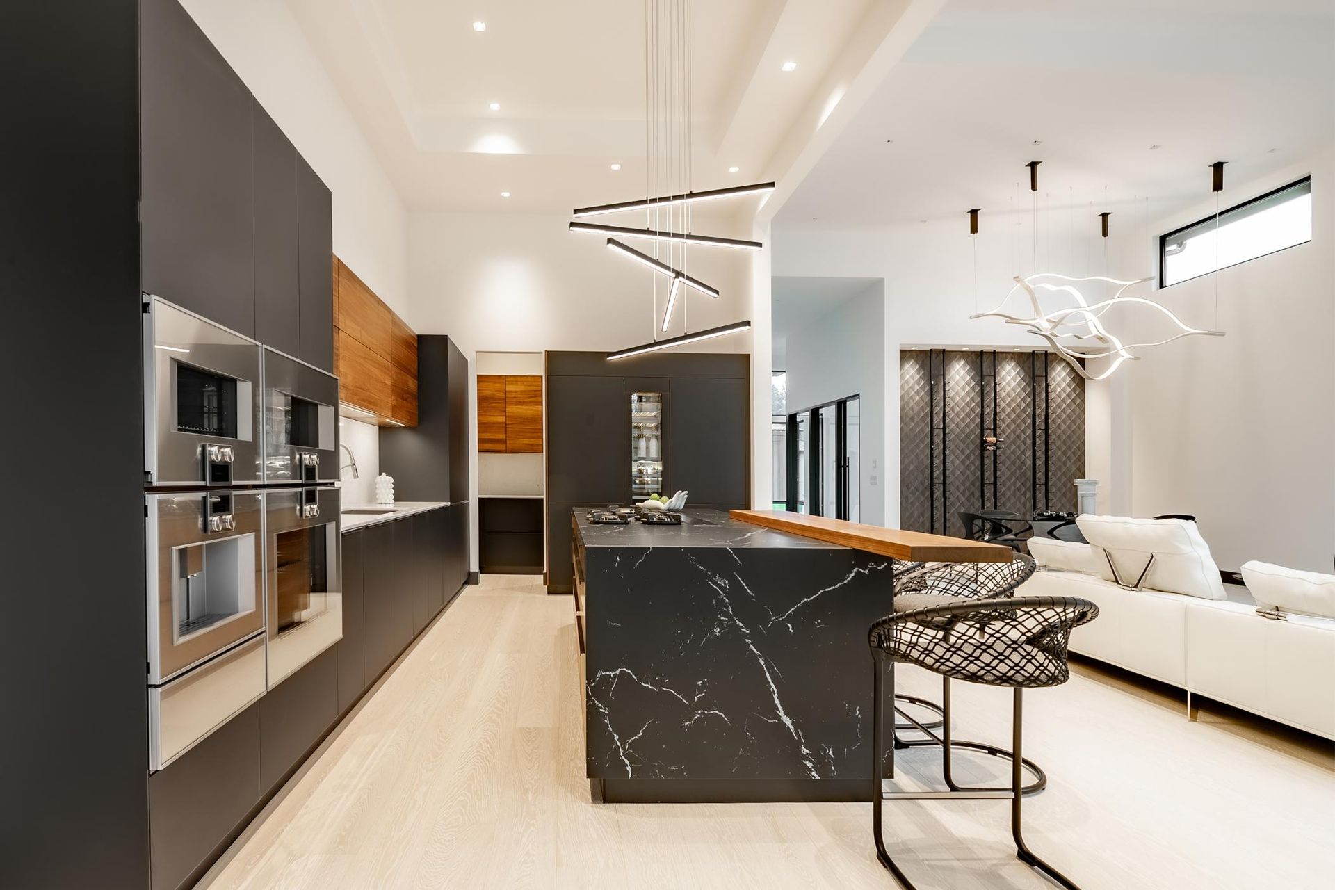 Modern kitchen with dark cabinetry, marble island, and light wood floors.