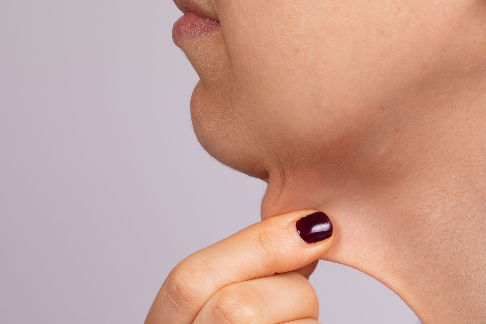 Person's hand touching the skin under their chin, demonstrating a double chin.