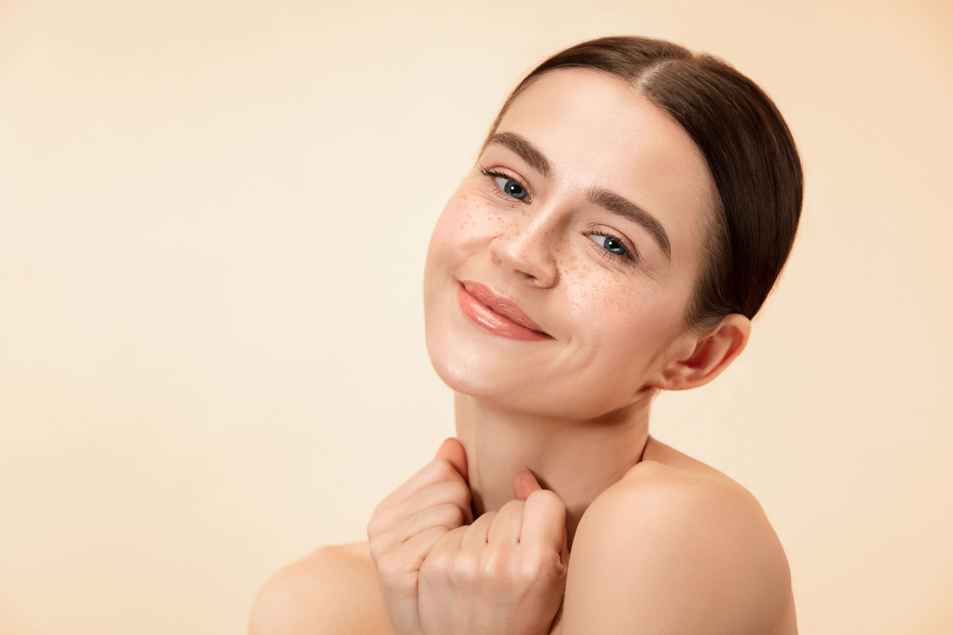 A woman with a beautiful face is smiling and touching her neck.