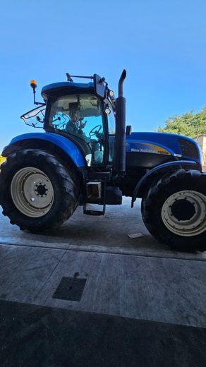 Trattore blu parcheggiato all'aperto su una superficie asfaltata sotto un cielo sereno.