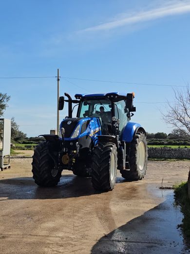 Un trattore blu su una strada di campagna sotto un cielo limpido.
