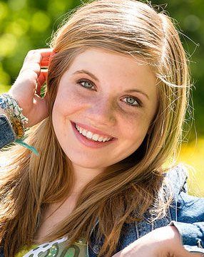 A young woman is smiling while talking on a cell phone.