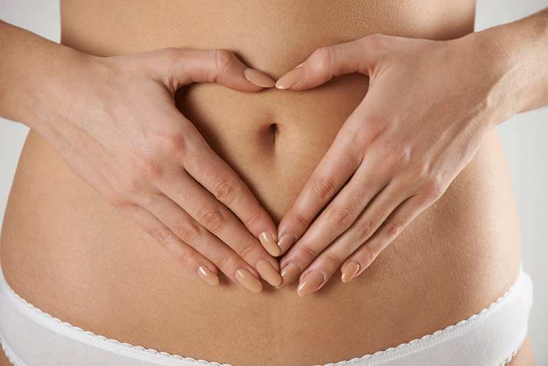 Eine Frau formt mit ihren Händen auf ihrem Bauch ein Herz.