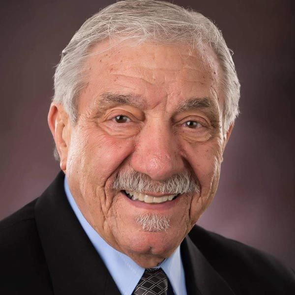 Smiling man with white hair and mustache in a suit