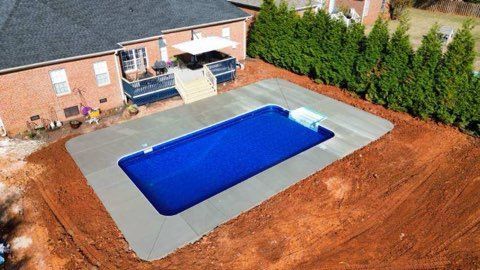 Backyard pool covered with a blue tarp beside a house and patio
