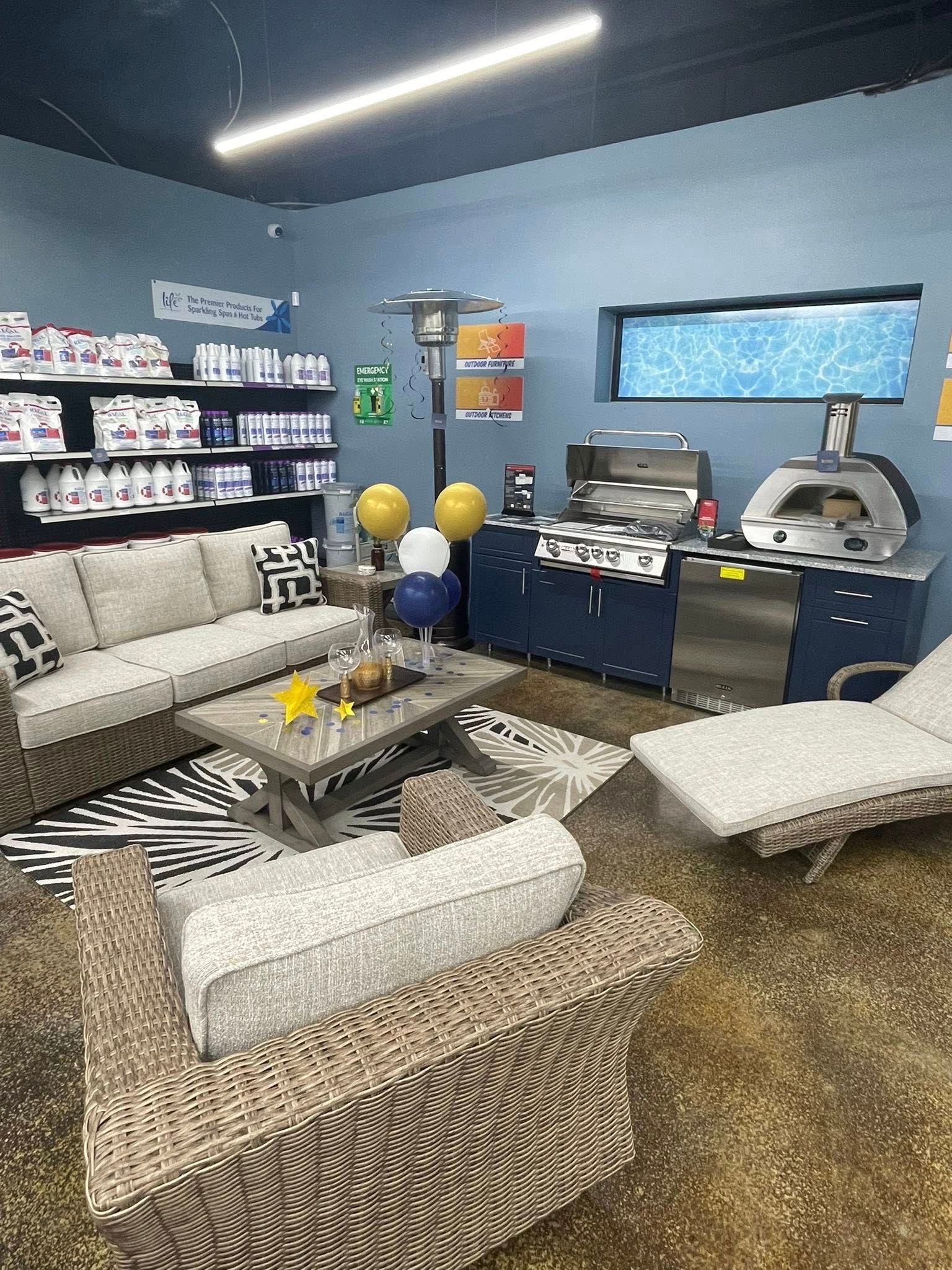 Modern lounge with gray seating, patterned ottomans, coffee table, wall shelves, and a game console area