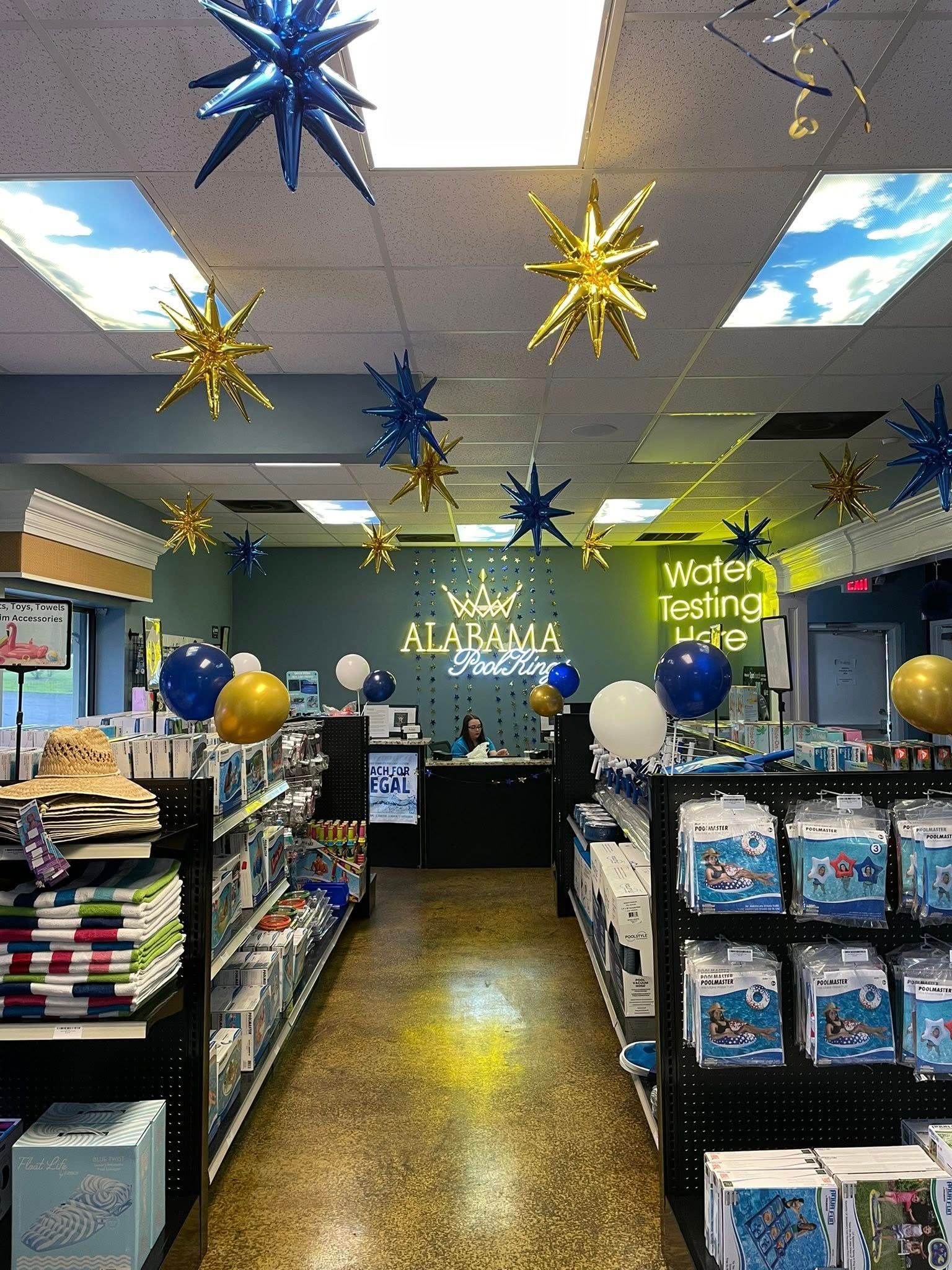 Decorated store aisle with blue and gold star ornaments hanging from the ceiling and shelves of merchandise below