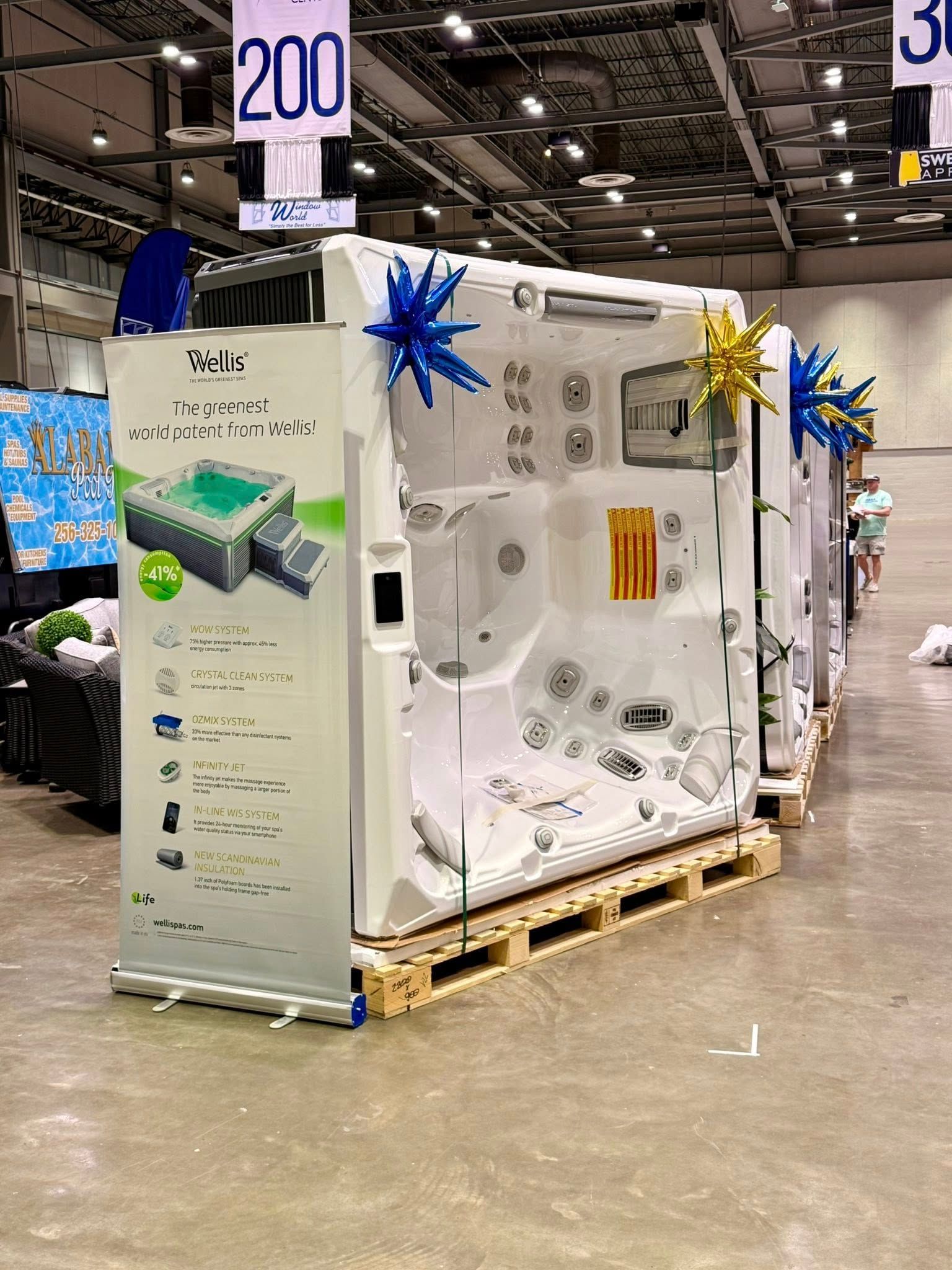 Trade show booth with white walls, blue and gold starbursts, and product displays on a pallet at an indoor expo.