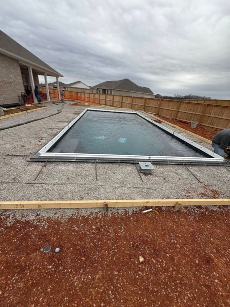 Rooftop with a rectangular skylight or pool opening surrounded by gravel under a cloudy sky