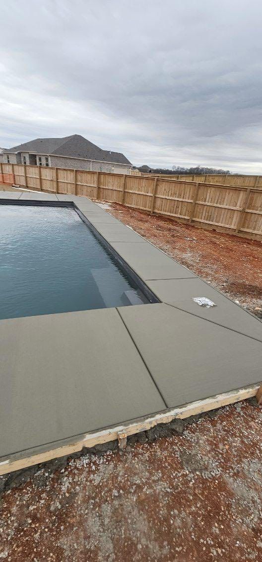 Backyard swimming pool with a beige fence, cloudy sky, and mountains in the distance