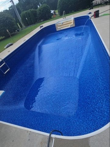 Blue in-ground pool with a partial water refill in a backyard setting