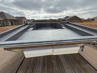 Capped rectangular backyard pool under construction, viewed from a deck with houses in the background