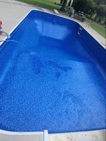 Blue in-ground swimming pool with rippling water, viewed from above outdoors.