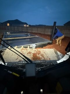 Person securing a rooftop panel at dusk from a bucket lift, with a brick wall and house in the background