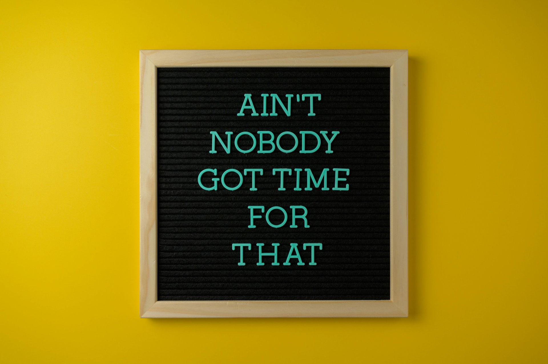 A black letter board with the words `` ain 't nobody got time for that '' on a yellow wall.