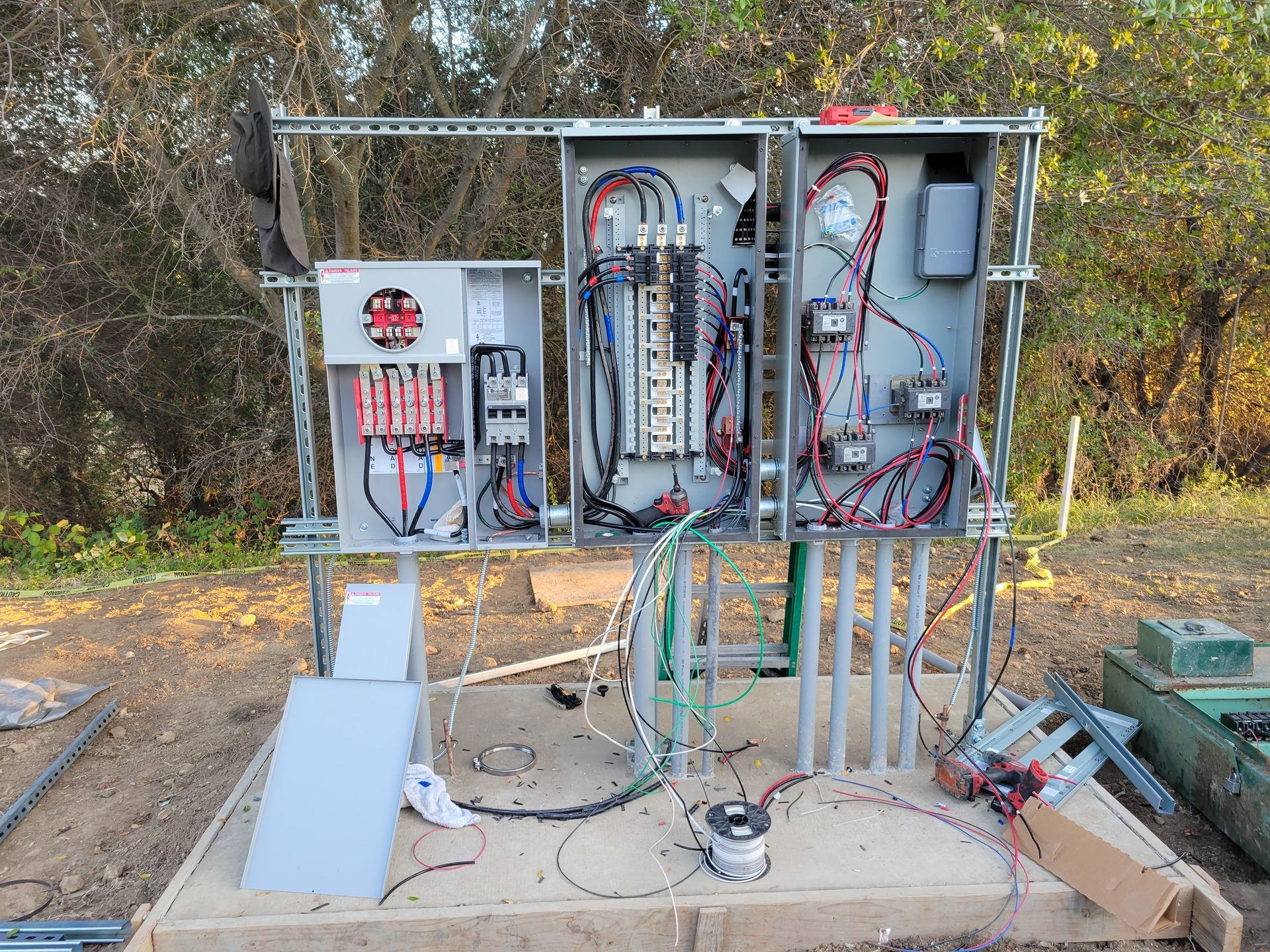 Open electrical control panels and wiring mounted outdoors on a metal frame.