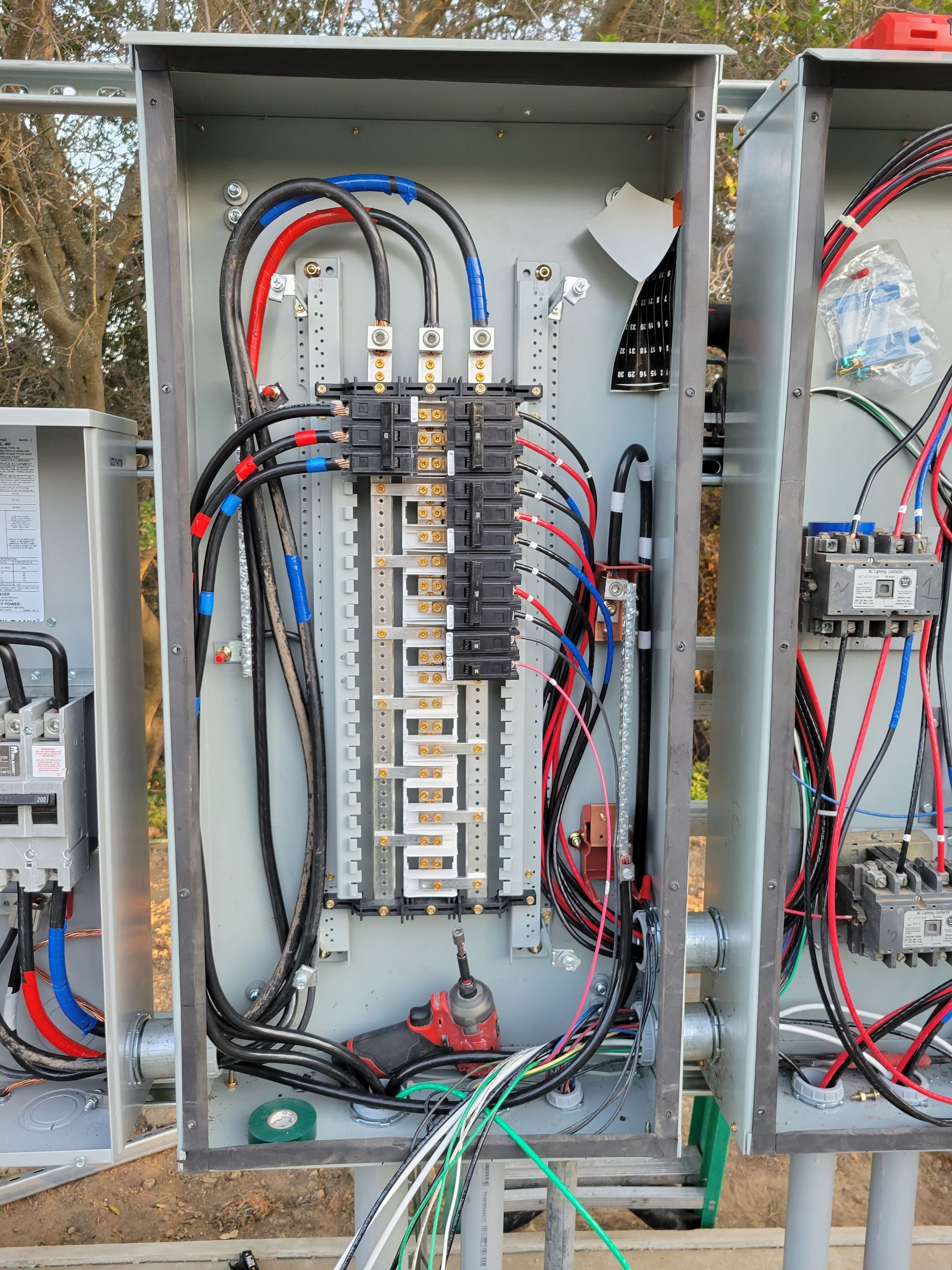 Open electrical breaker panel with multicolored wires and circuit breakers in a metal cabinet.