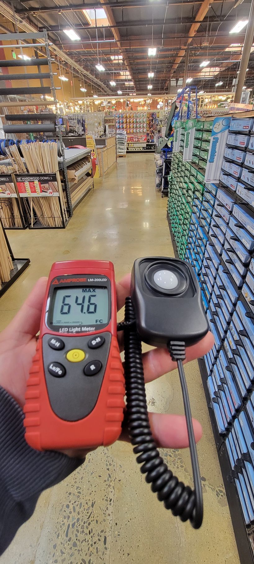 Warehouse aisle with a handheld barcode scanner and digital temperature meter in the foreground