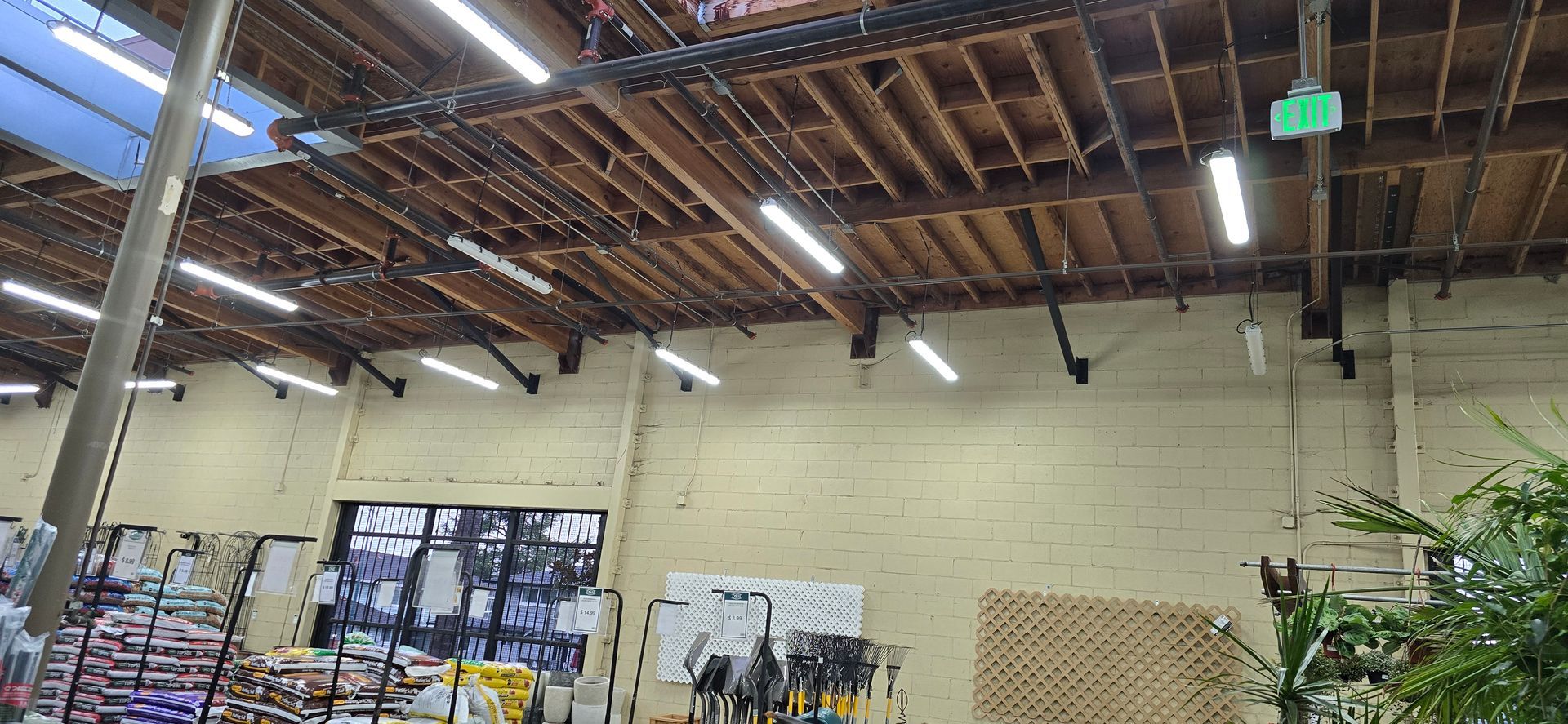 Indoor market with wooden ceiling, hanging lights, and market stalls against a brick wall.
