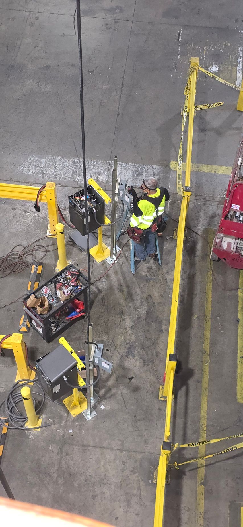 Overhead view of two workers in high-visibility gear handling equipment on a wet industrial worksite