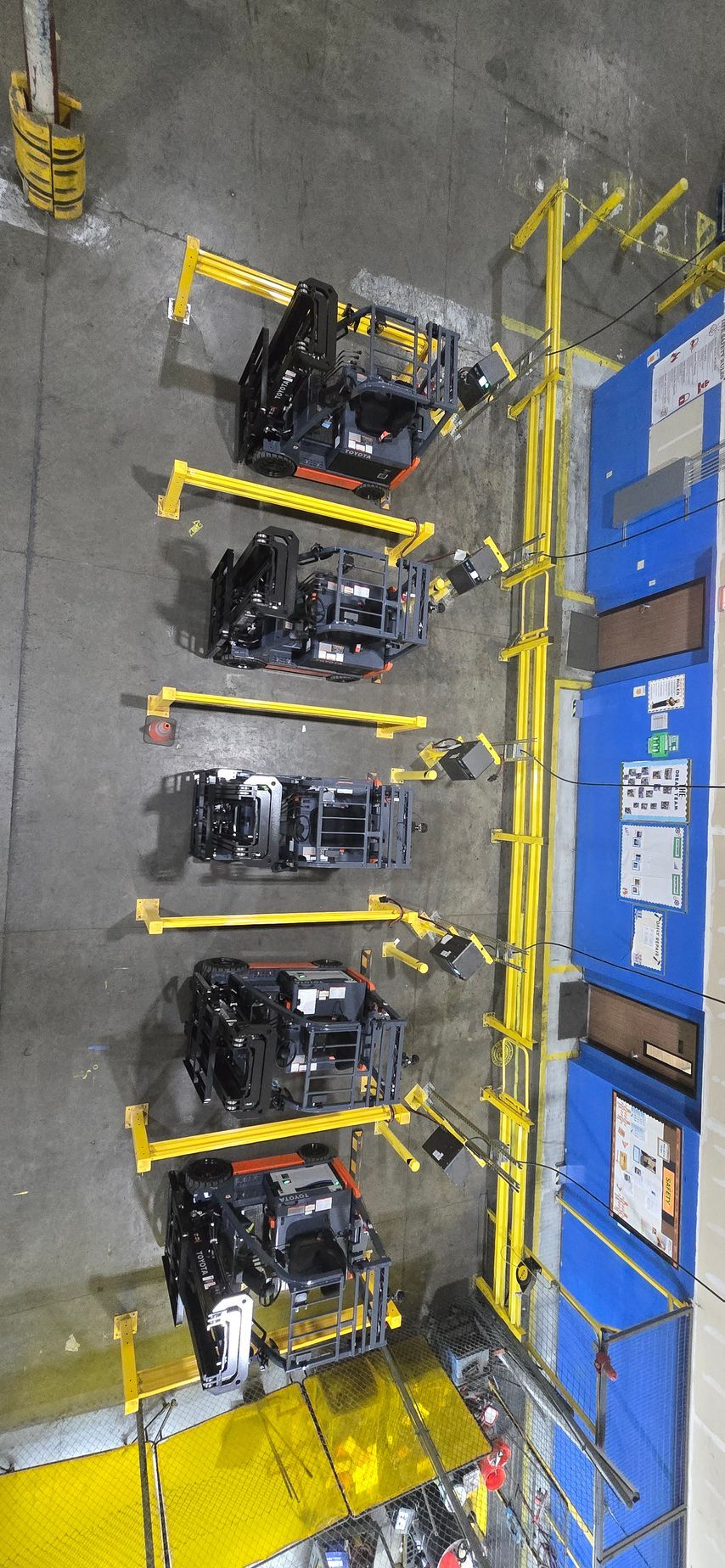 Yellow industrial rack with black equipment modules beside blue electrical panels in a utility room