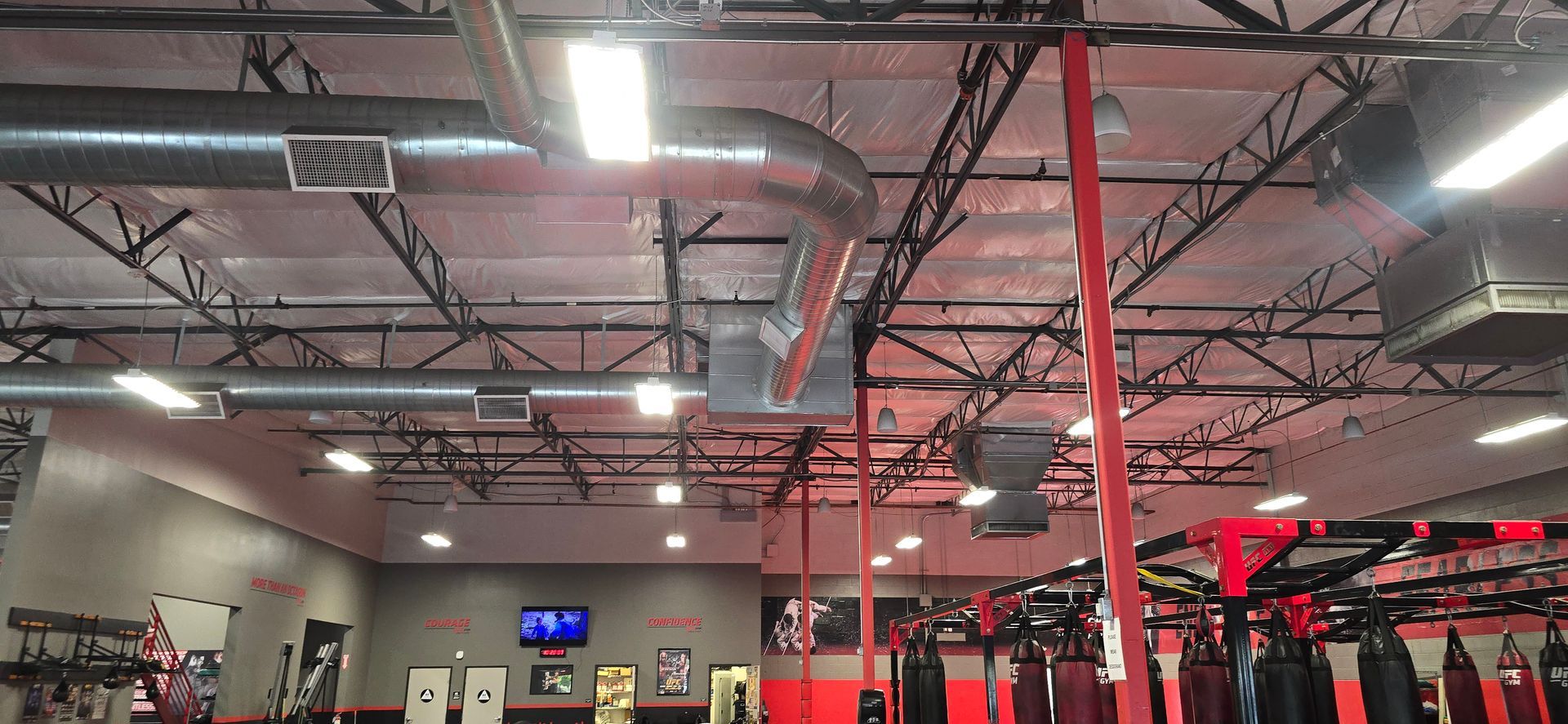 Gym interior with red and black equipment under exposed ceiling lights