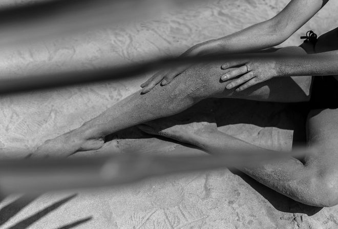 Two people seated on a floor, each reaching toward a dark object between them.