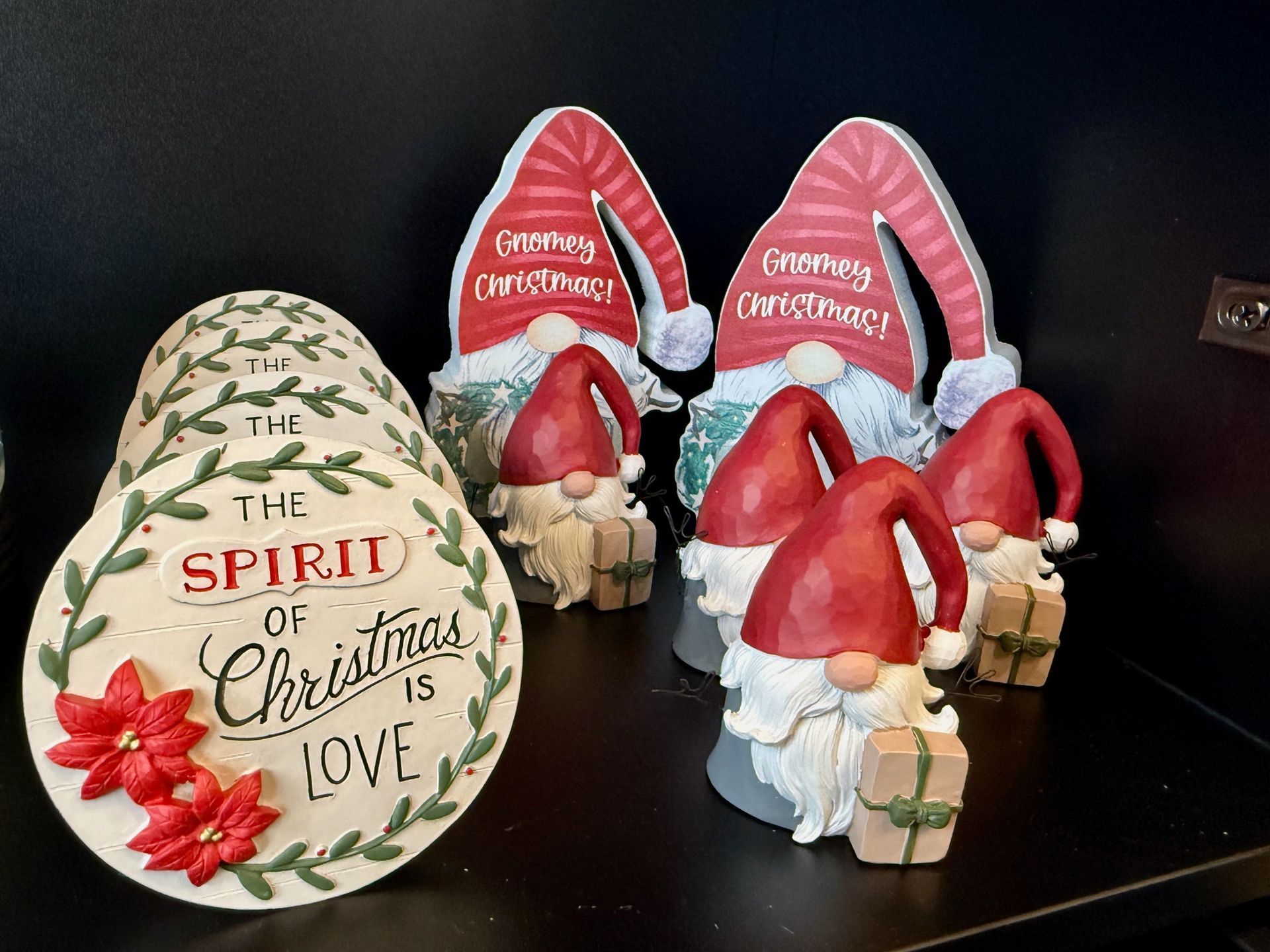 A group of christmas gnomes are sitting on a table next to a sign that says the spirit of christmas is love.