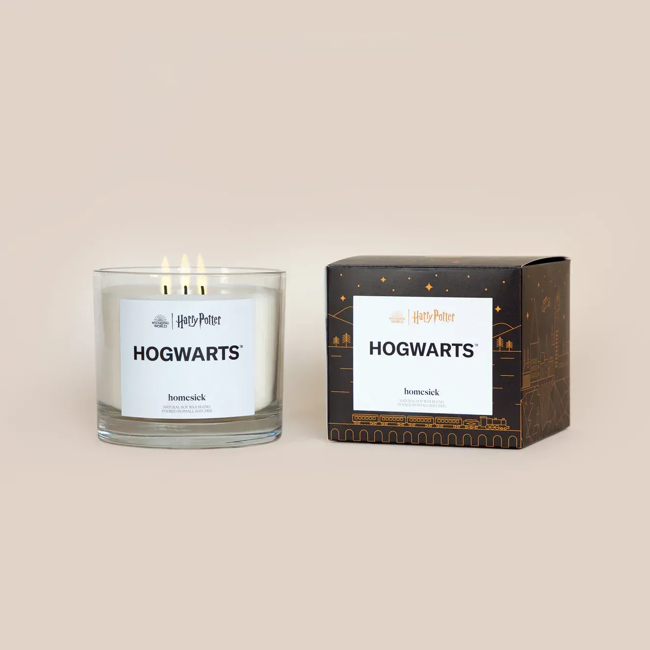 A candle in a glass next to a box that says hogwarts.