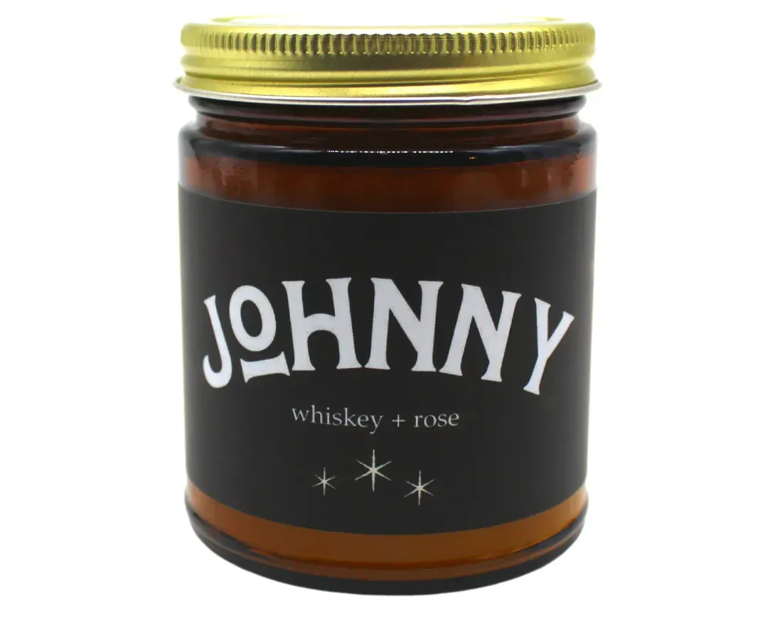 A jar of johnny whiskey rose candle with a gold lid