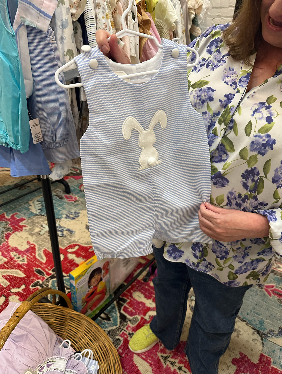A woman is holding a baby outfit with a bunny on it.
