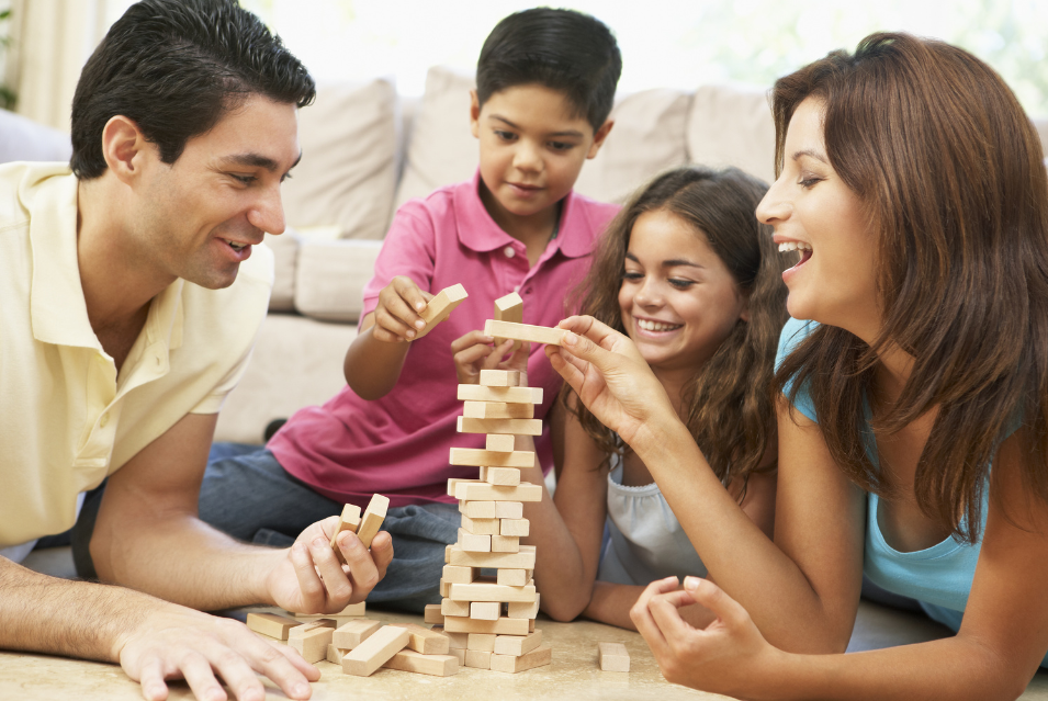 A family playing a board game together, laughing and smiling while spending time together.