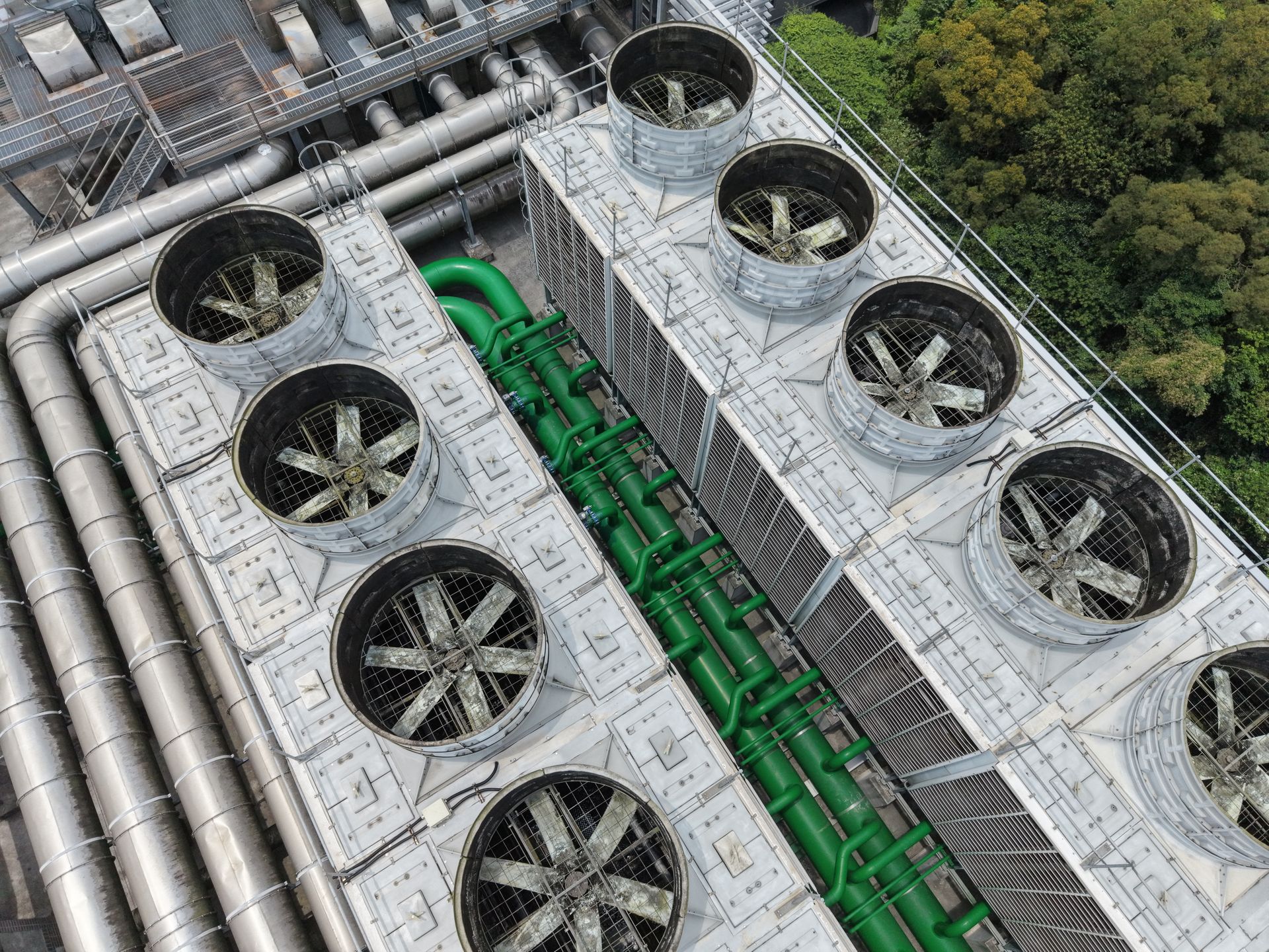 Vue aérienne de tours de refroidissement industrielles CVC avec de grands ventilateurs et des tuyauteries vertes sur un toit