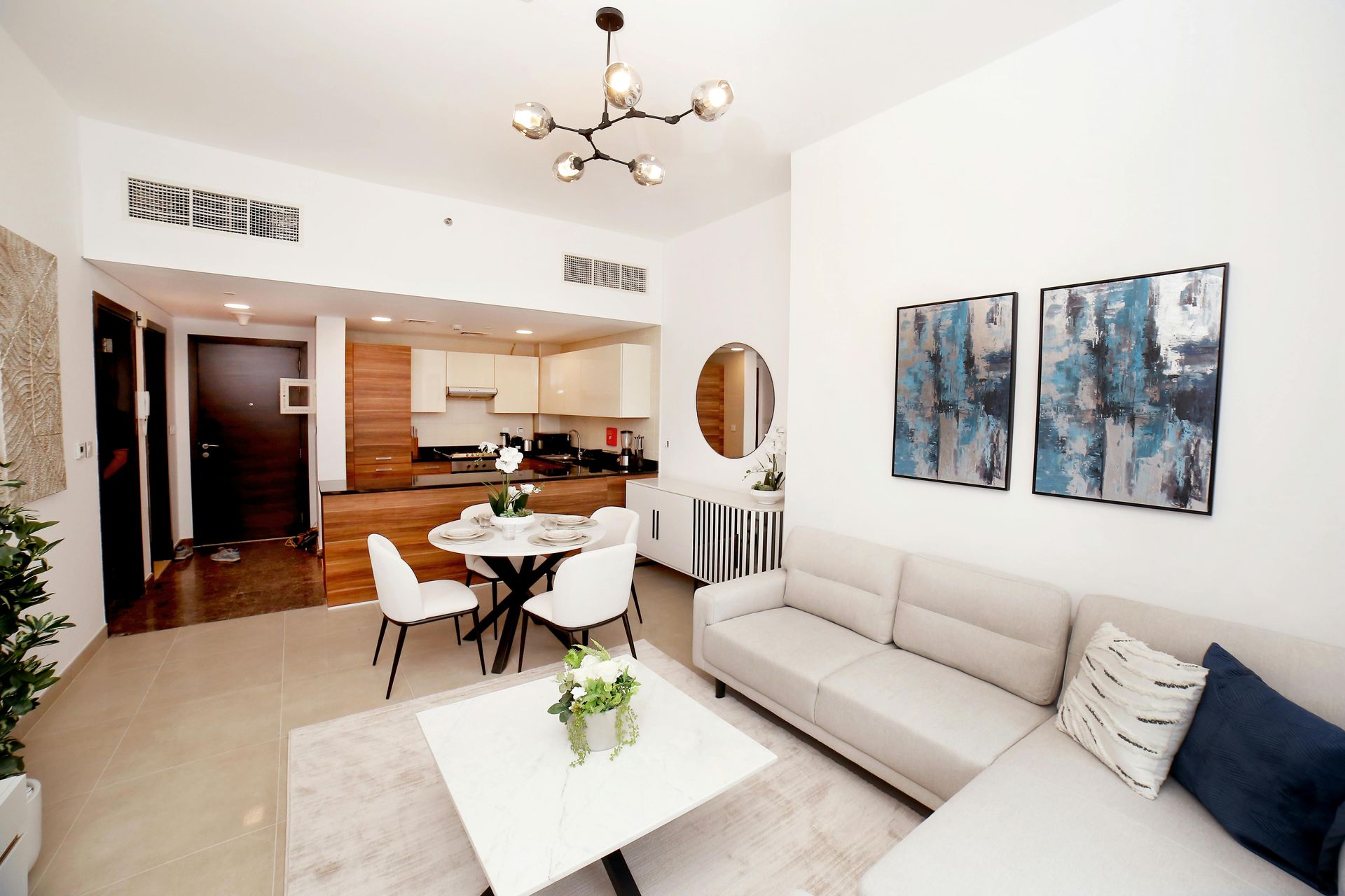A living room with a couch , table and chairs and a kitchen in the background.